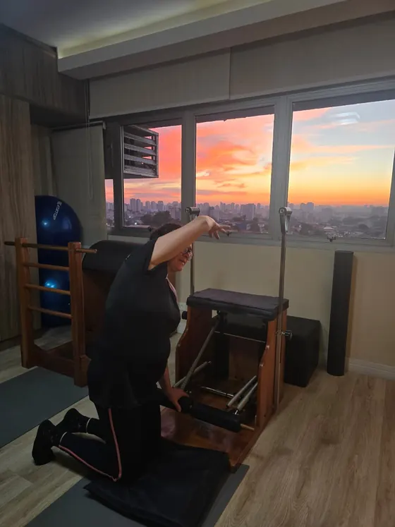 Estúdio com aparelhos de pilates e pôr do sol pela janela